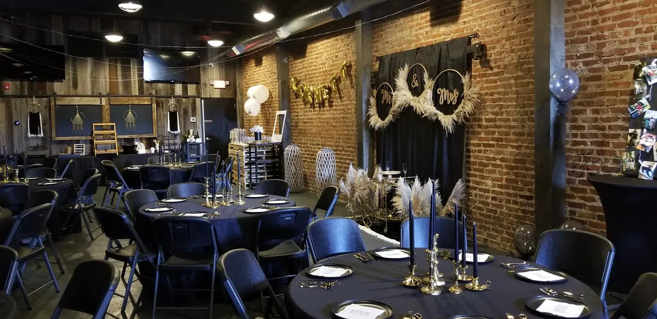 Indoor reception with black-and-gold place settings and exposed brick walls