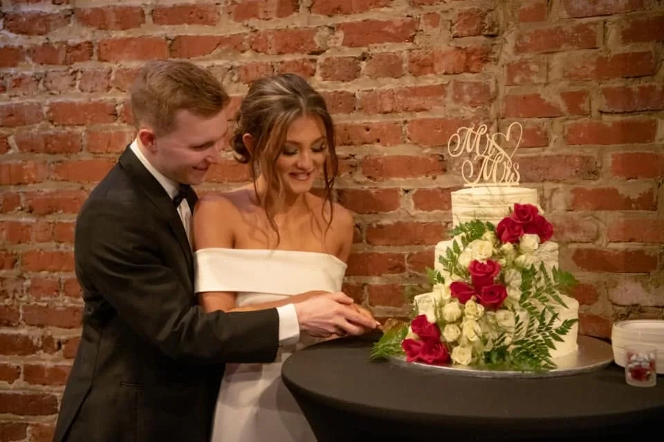 Bride and groom cutting their cake against the exposed brick wall