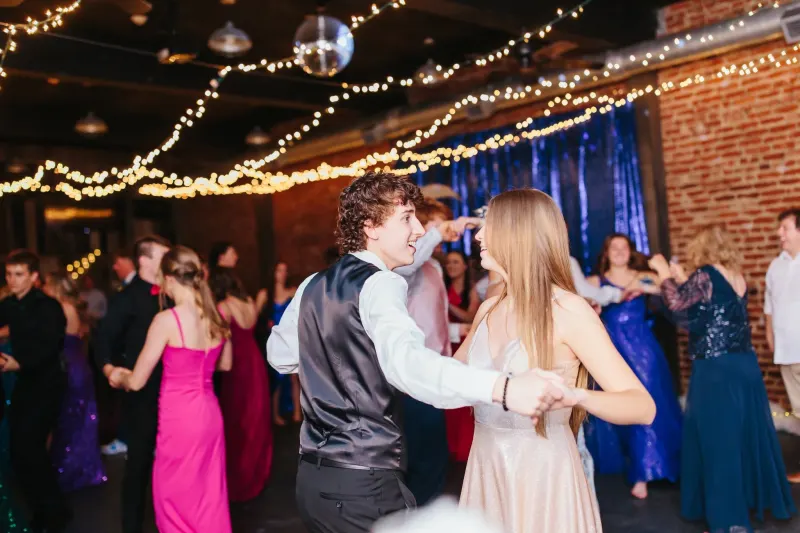 Prom guests dancing under string lights and a disco ball