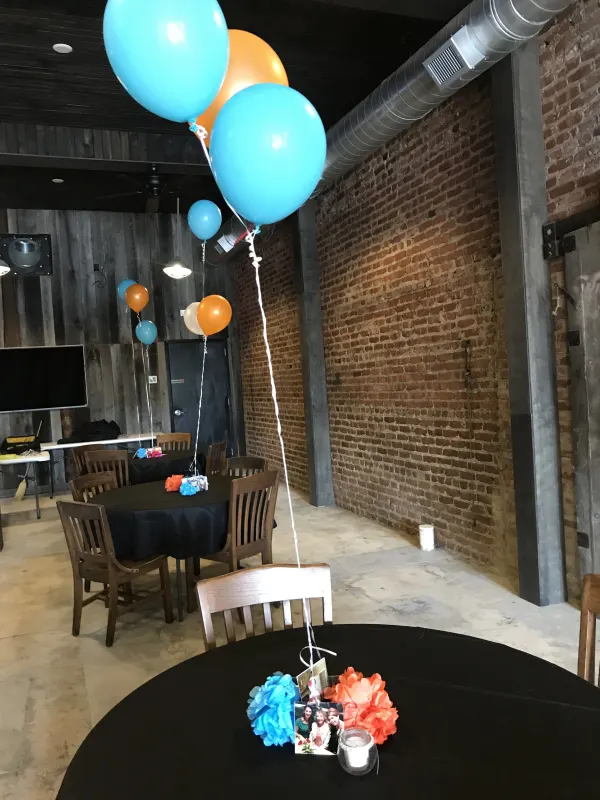 Indoor party setup with balloons and exposed brick