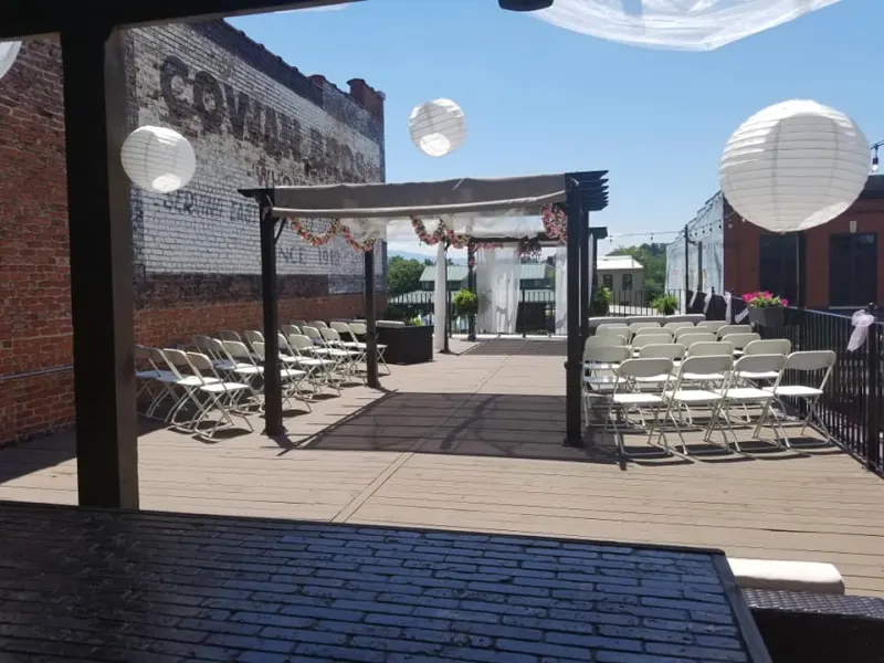 Rooftop ceremony with a draped arch under a blue sky