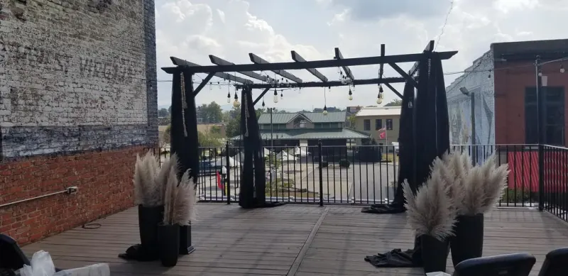 Rooftop ceremony arch draped in black with Edison string lights