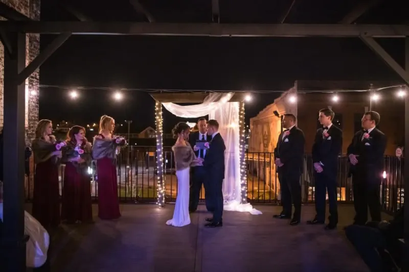 Evening rooftop wedding ceremony lit by string lights