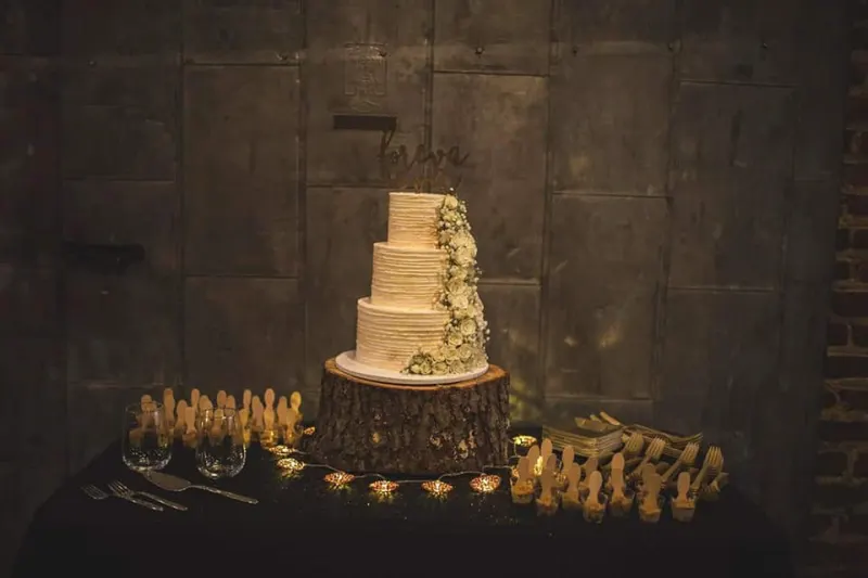 Tiered wedding cake on a wood slice with fairy lights