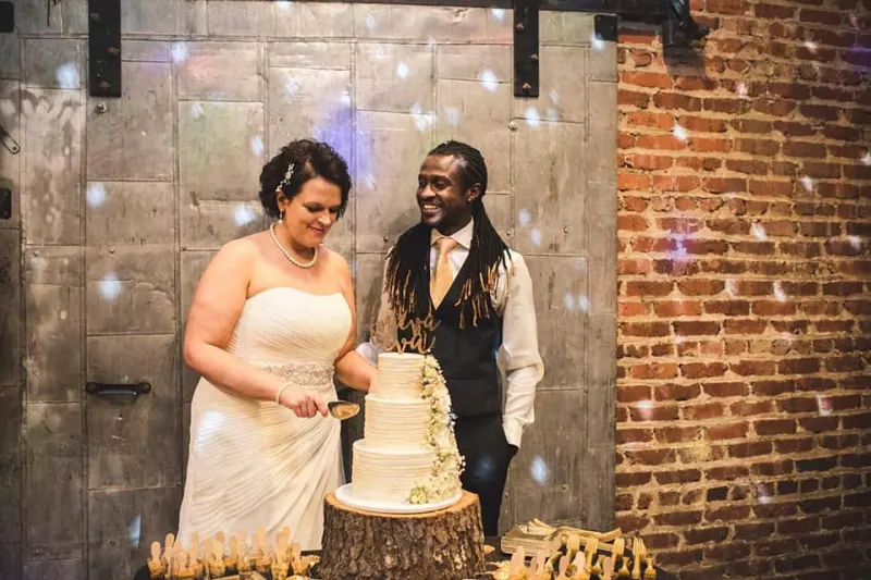 Couple cutting a wedding cake on a wood-slice stand