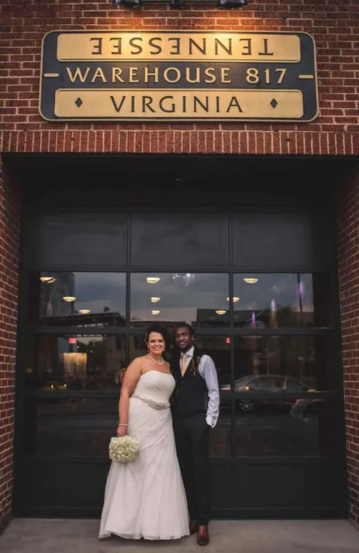 Bride and groom beneath the Warehouse 817 sign at the entrance